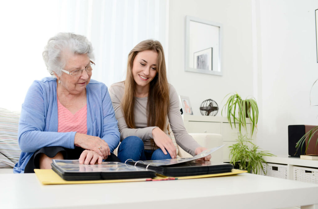 A daughter going through some old family pictures with her elderly mother to recollect good memories.