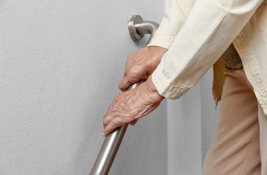 An elderly woman holding the rails for support as she walks down a flight of stairs.