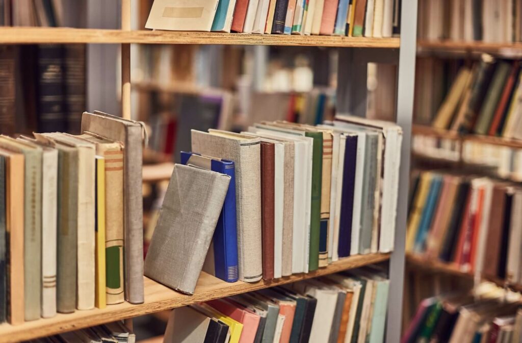 Books sit on a shelf of a home library, ready to be explored.