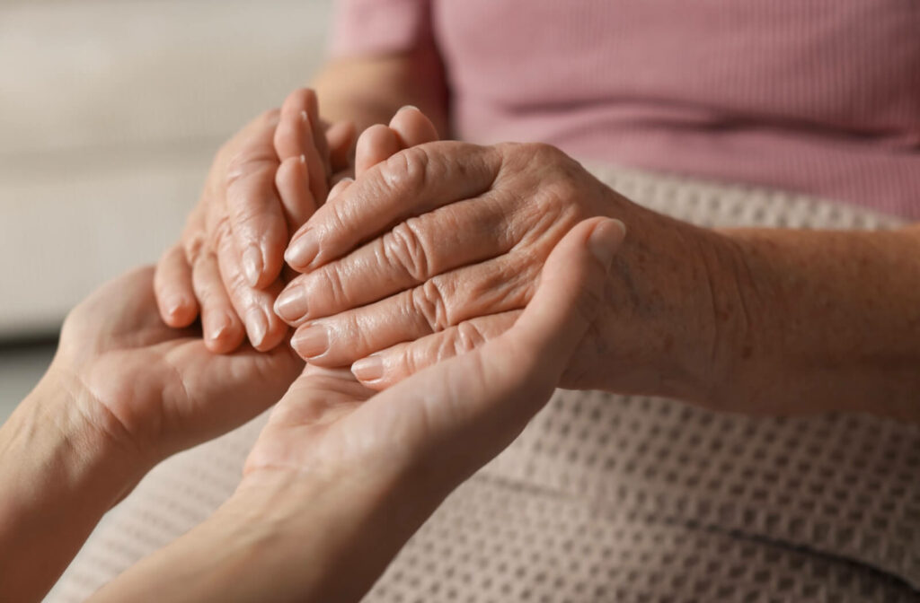 Close-up of someone holding hands with an older senior woman.