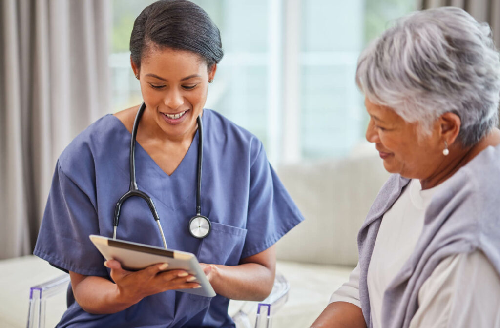 A caregiver showing an older adult the results of their recent health checkup on a tablet in a Care Suite in senior living.